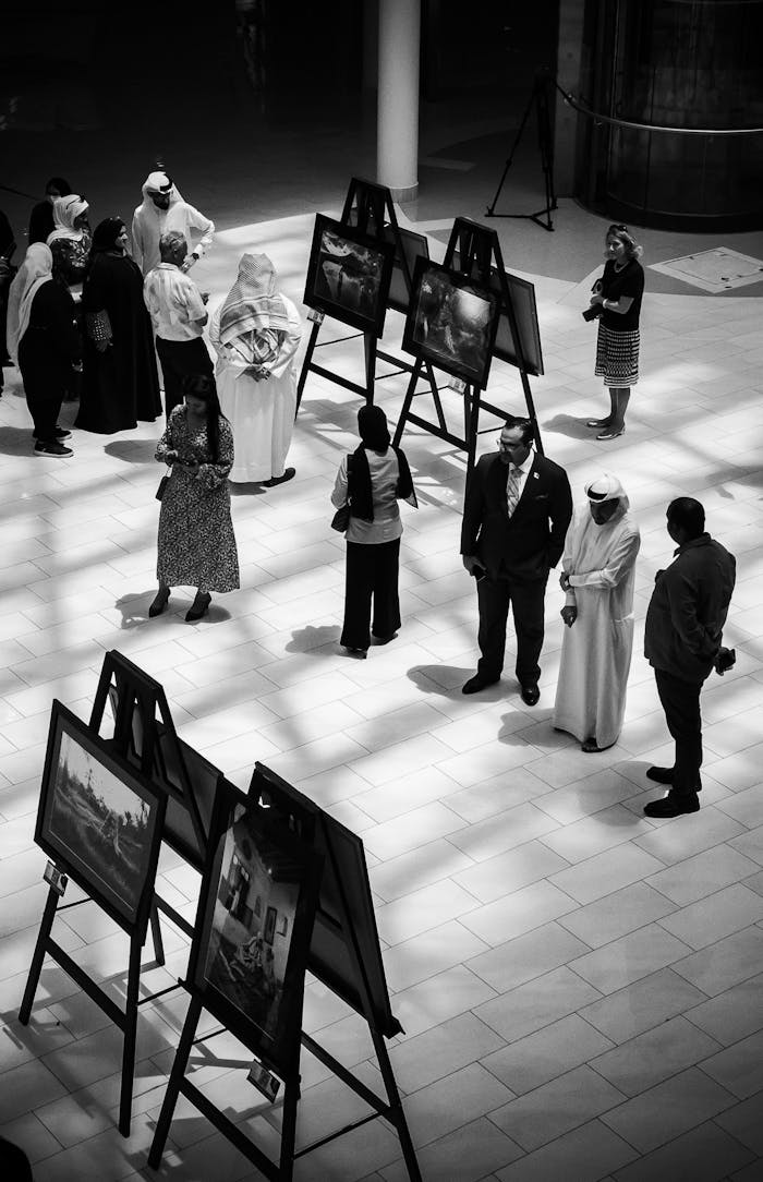 Crafting Captivating Headlines: Your awesome post title goes here A black and white image of people at an indoor art exhibition observing paintings.