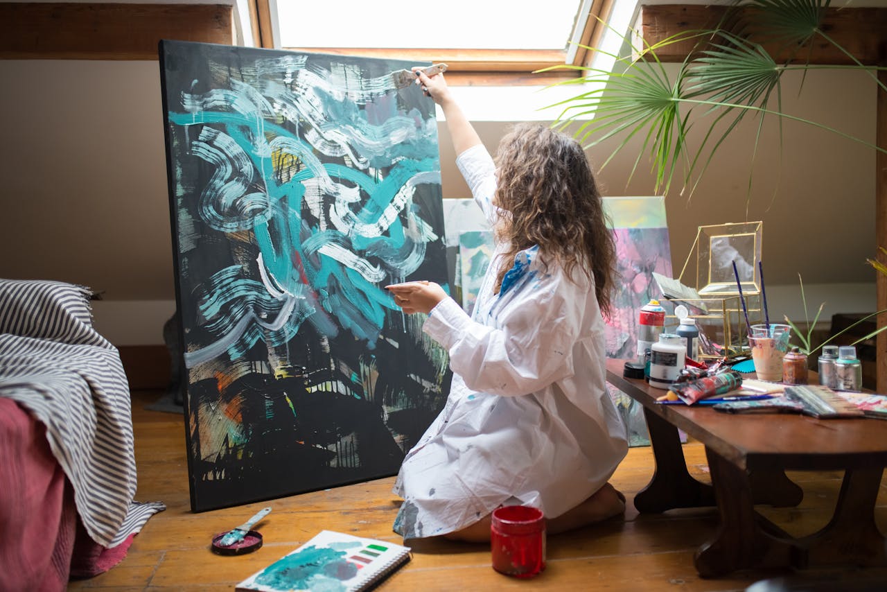 who-we-are An artist creates abstract art on a large canvas in a cozy attic studio.